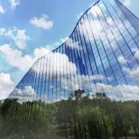Modern building with a reflection of trees and blue skies showing the connection between sustainable development